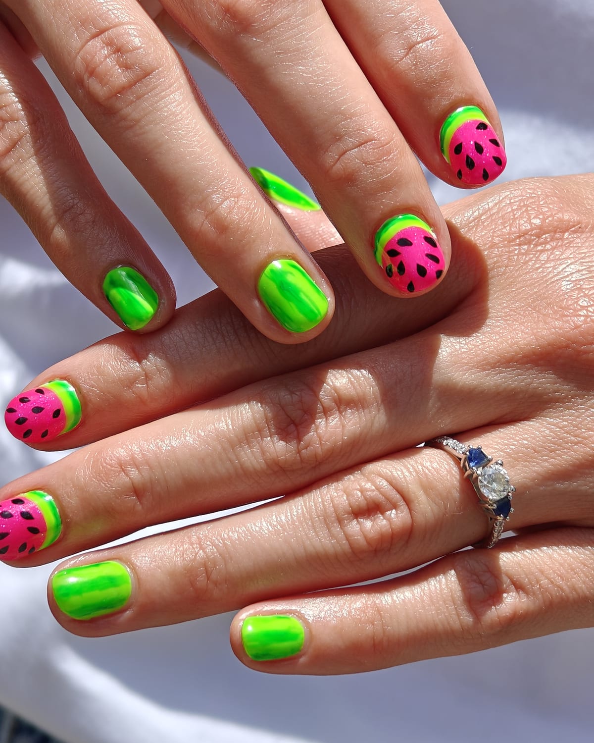 Almond nails alternating neon green chrome with watermelon pink tips, black painted seeds and a lime rind stripe.