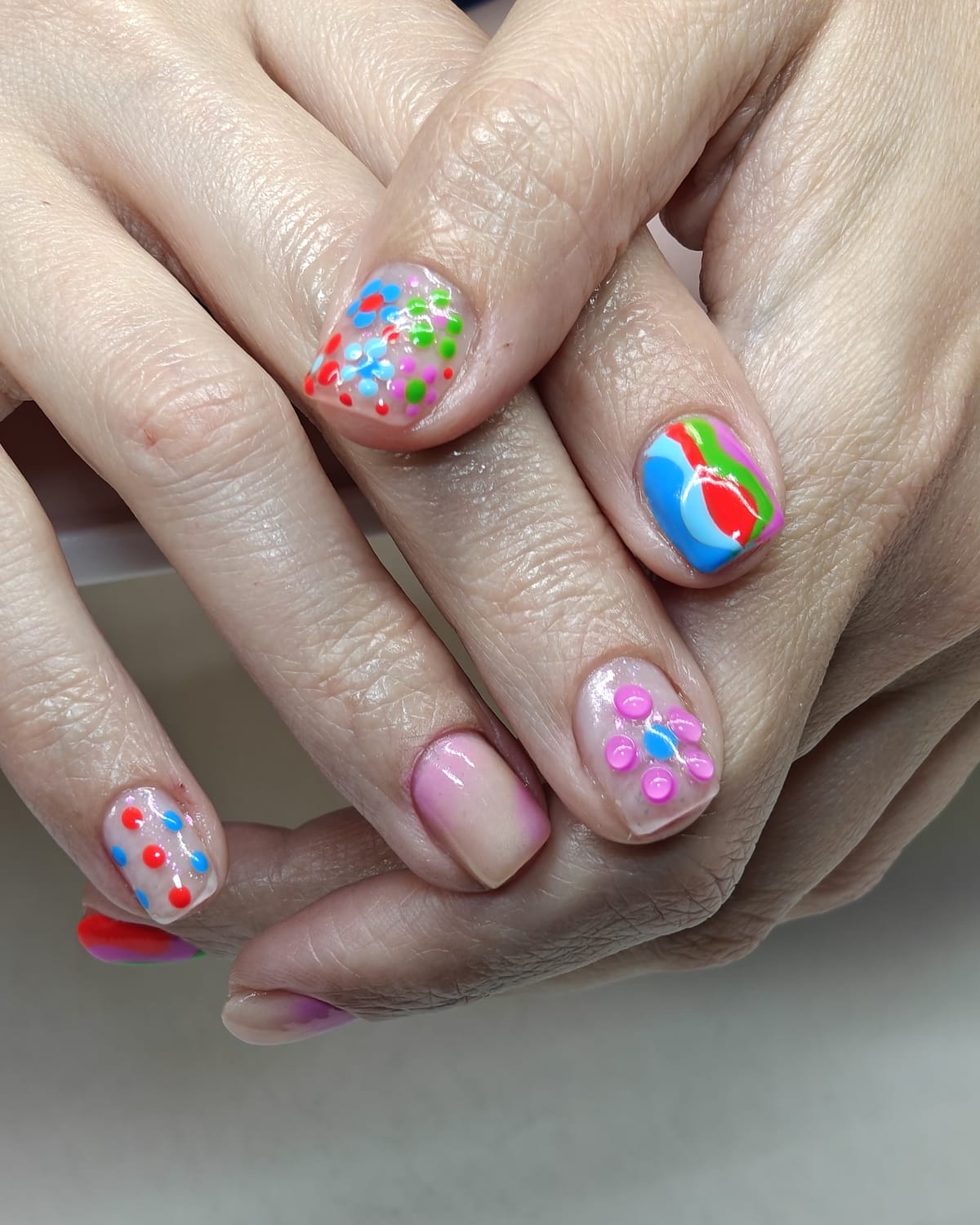 Nail work from Only Nails Beauty — short natural nails with neon confetti dots and a painted beach-ball accent nail.