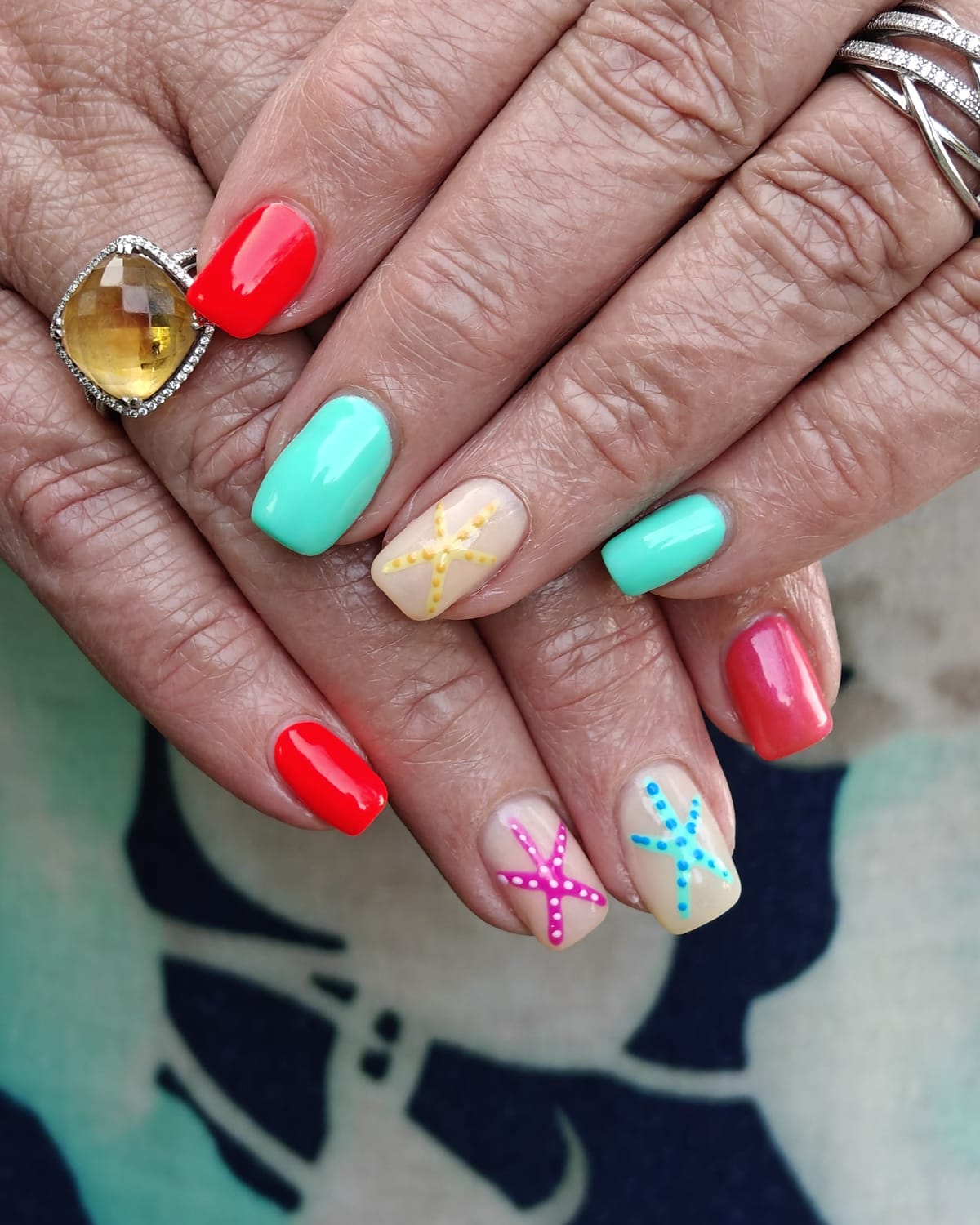 Nail work from Only Nails Beauty — coral red and mint green square nails with dotted starfish nail art.