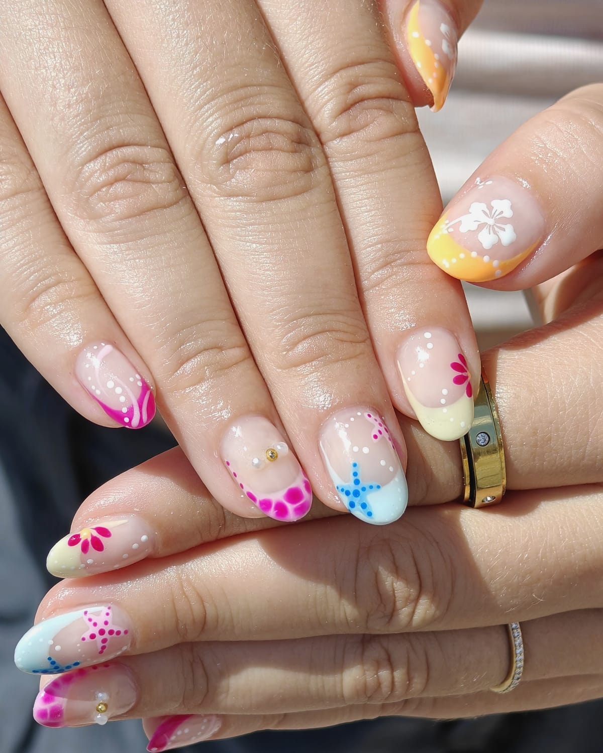 Nail work from Only Nails Beauty — a tropical French manicure with pink, blue, yellow and orange tips, hand-painted starfish and hibiscus flowers.